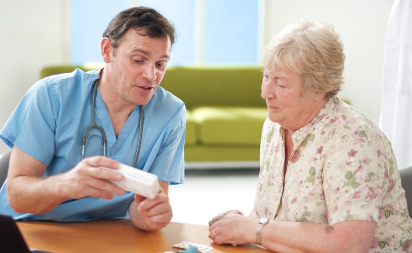 Caregiver assisting an older woman with medication